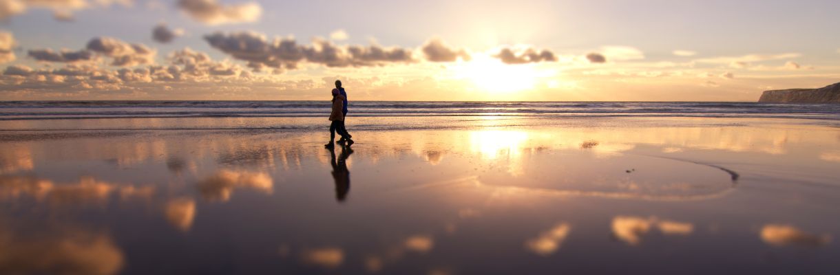 Couple walking along the beach in winter with sunset